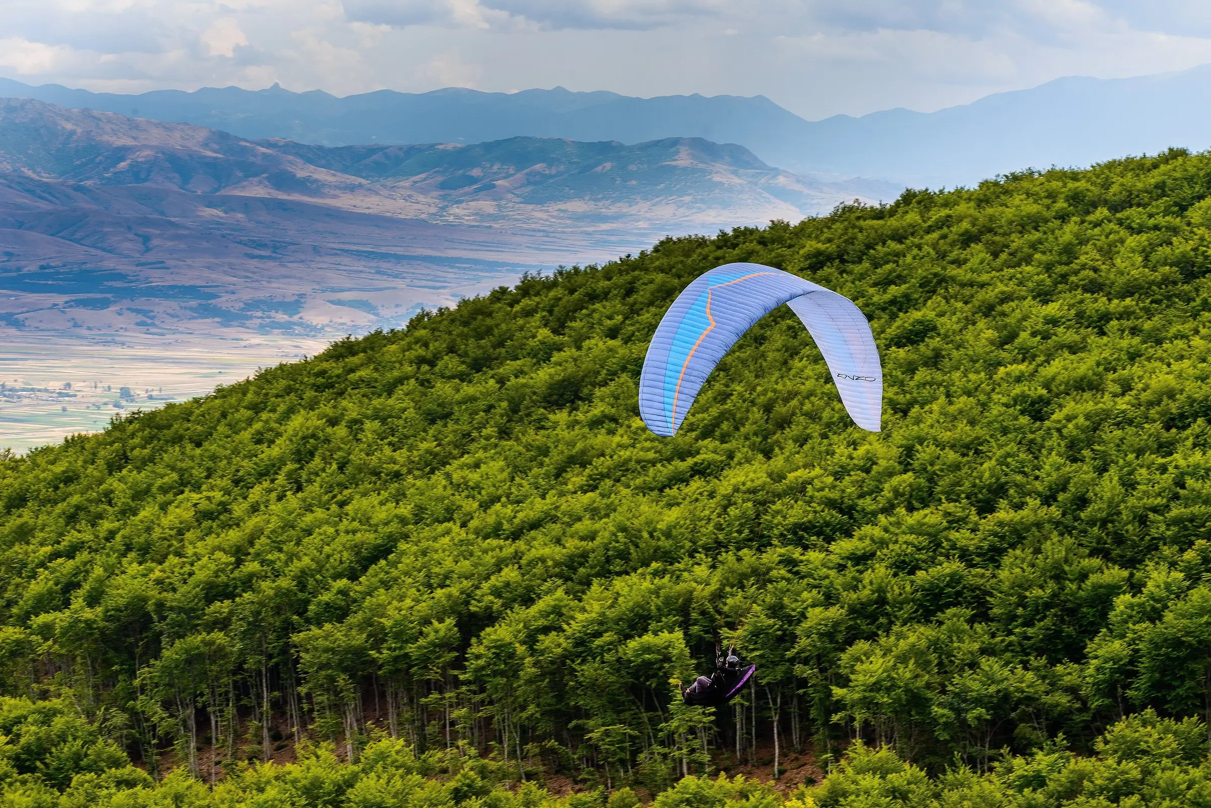 Paraglider flying above the forest at Krusevo