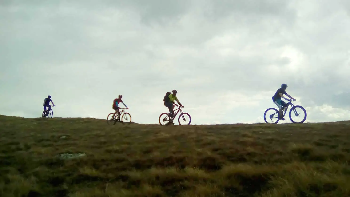 Mountain bikers riding along a ridge against the sky