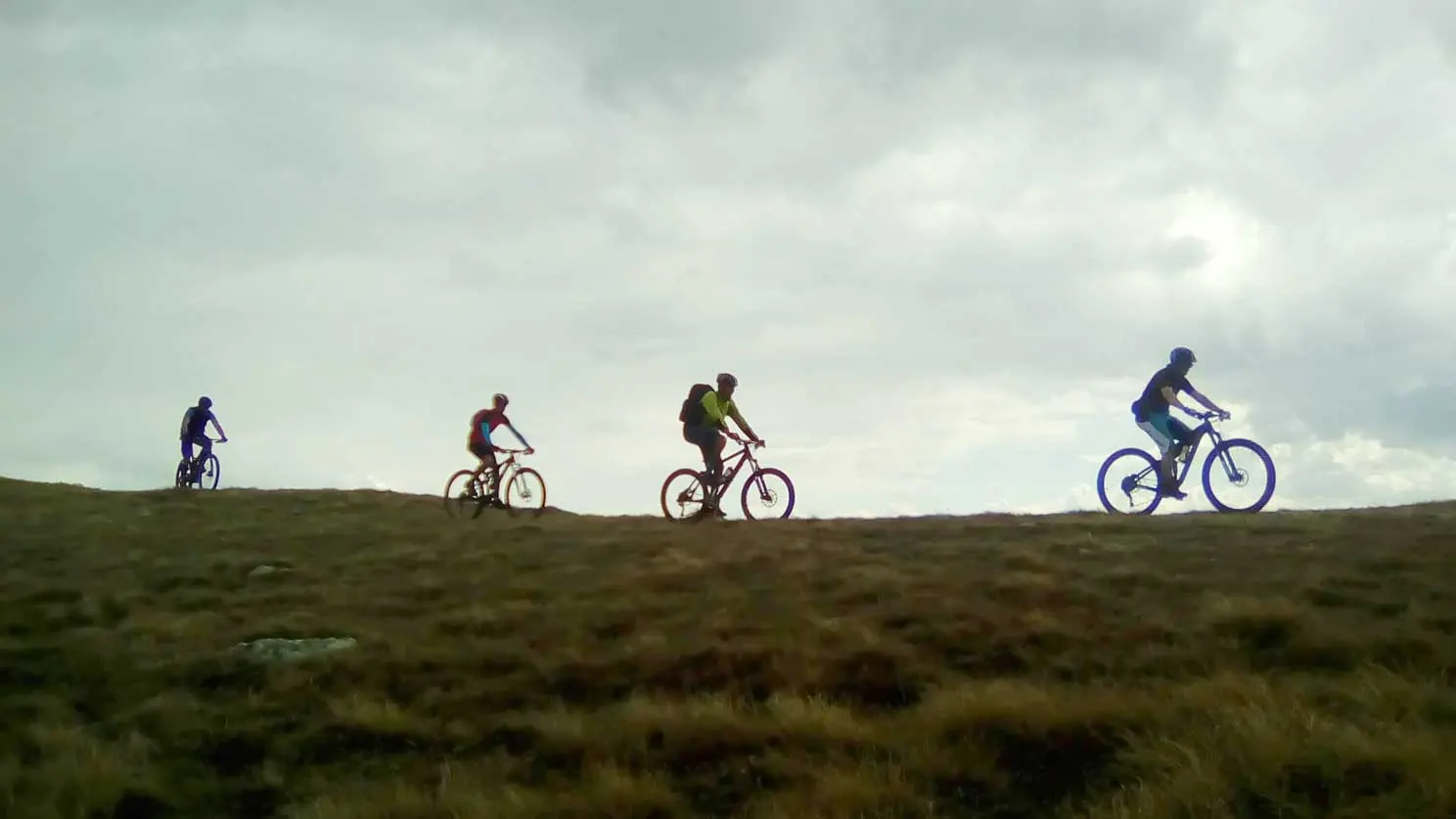 Mountain bikers riding along a ridge against the sky