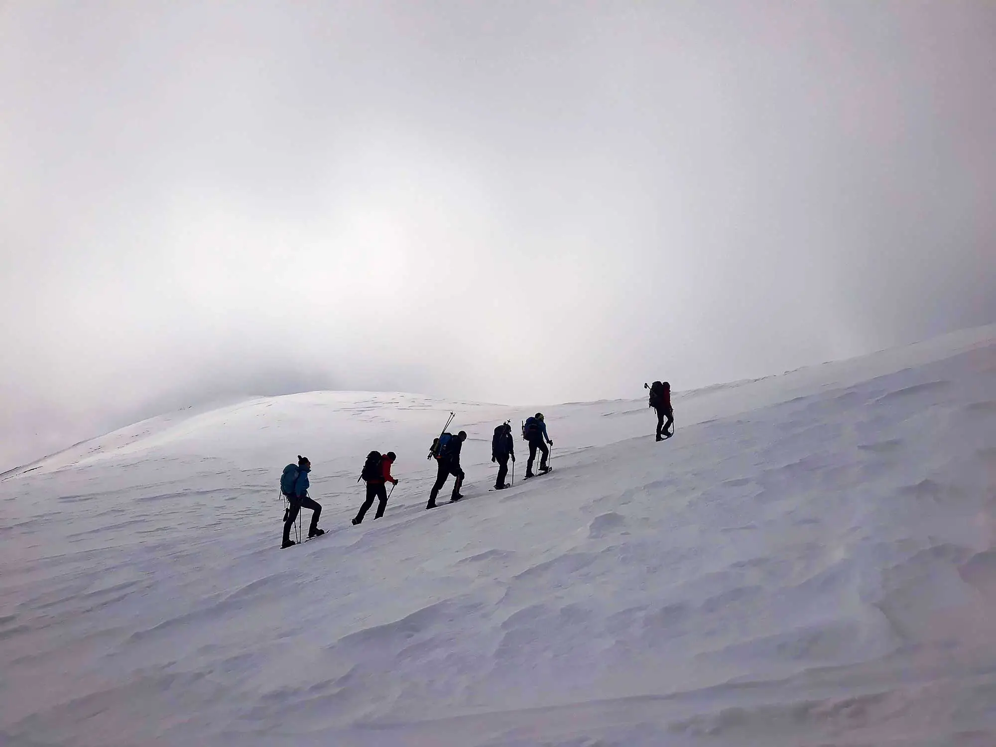 Line of hikers climbing a snowy slope